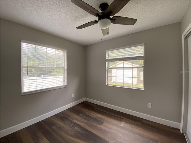 empty room featuring ceiling fan, dark wood-type flooring, and a textured ceiling