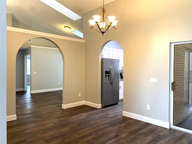 empty room featuring lofted ceiling, a textured ceiling, dark hardwood / wood-style floors, and a chandelier