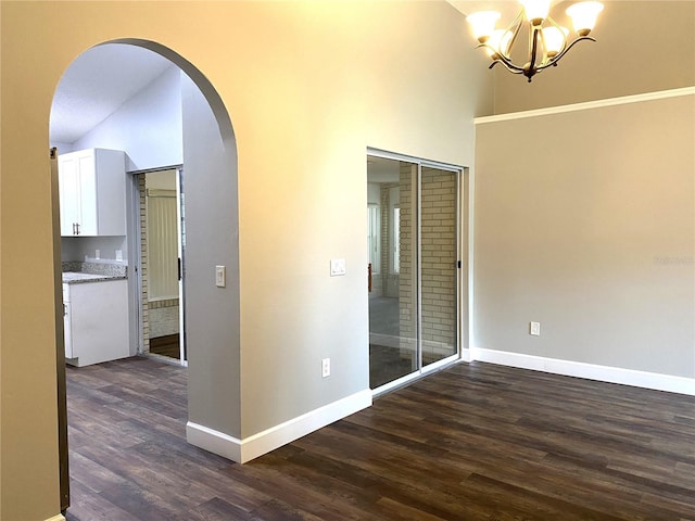 spare room with high vaulted ceiling, dark hardwood / wood-style floors, and an inviting chandelier