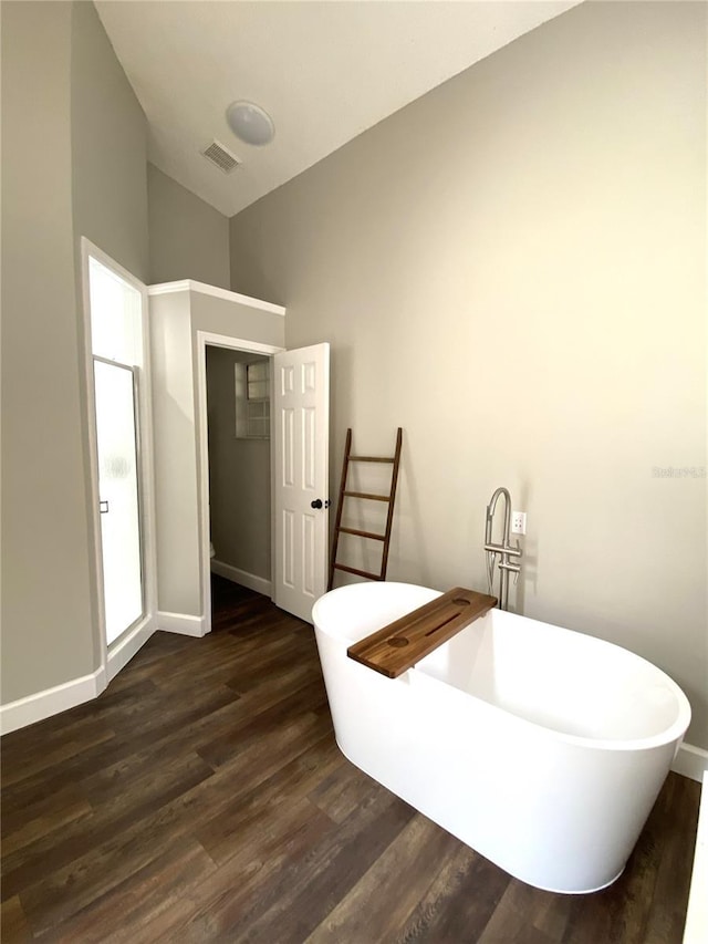 bathroom with vaulted ceiling, hardwood / wood-style floors, and a bathtub