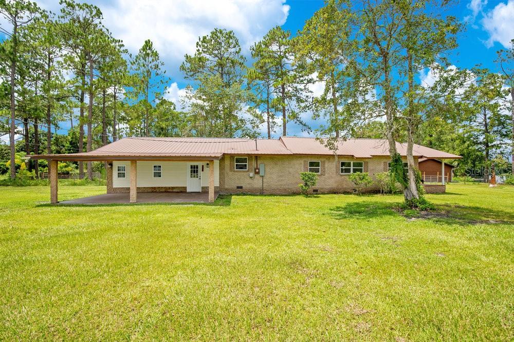 back of property featuring crawl space, metal roof, and a yard