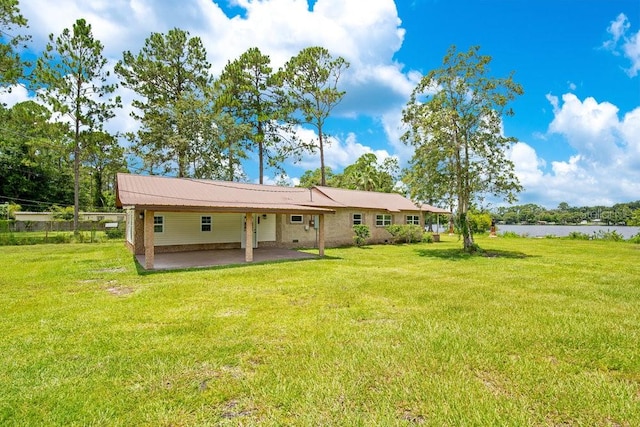 back of property with a water view and a lawn