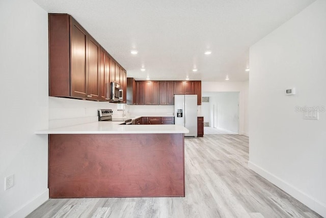 kitchen featuring stainless steel appliances, light hardwood / wood-style flooring, and kitchen peninsula