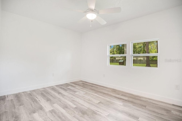 spare room featuring a ceiling fan, light wood-style flooring, and baseboards