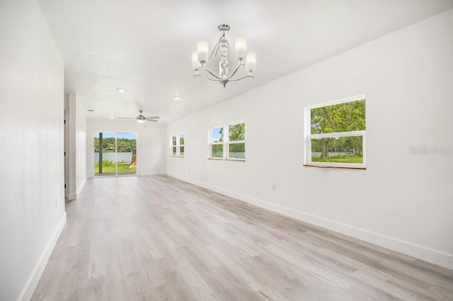 unfurnished room with baseboards, light wood finished floors, and ceiling fan with notable chandelier