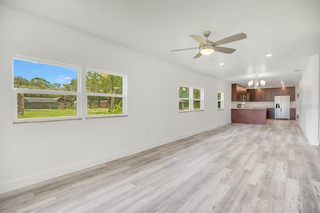 unfurnished living room with light wood-type flooring and ceiling fan with notable chandelier