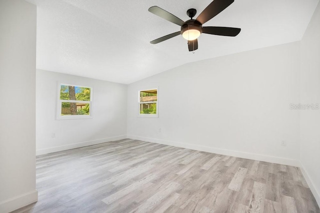 unfurnished room featuring light wood-type flooring, baseboards, a textured ceiling, and lofted ceiling