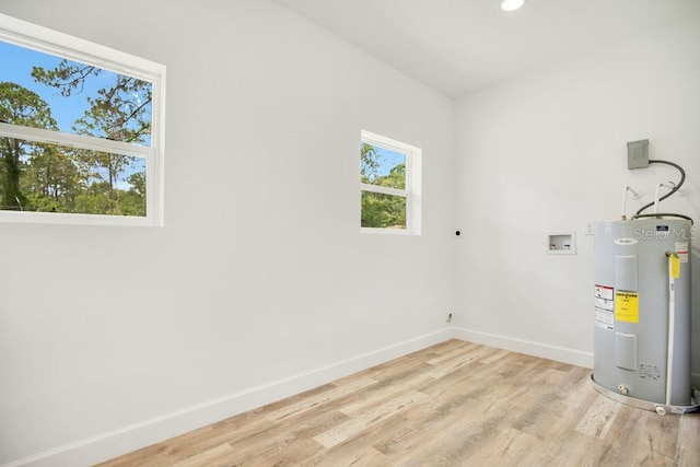 washroom with water heater, hookup for a washing machine, hookup for an electric dryer, and light wood-type flooring