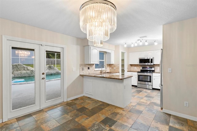 kitchen with kitchen peninsula, french doors, stainless steel appliances, sink, and white cabinetry