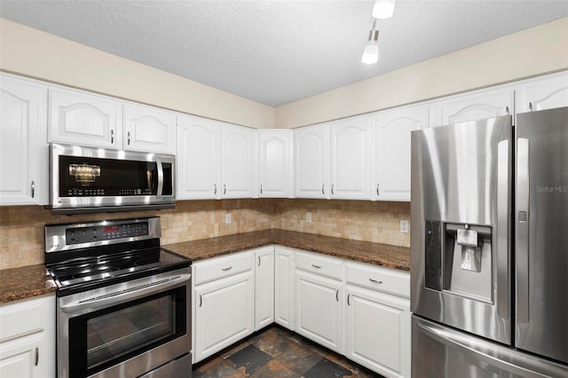 kitchen featuring dark stone countertops, white cabinets, stainless steel appliances, and a textured ceiling