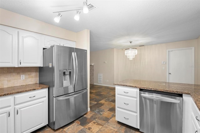 kitchen featuring dark stone countertops, white cabinetry, a notable chandelier, and appliances with stainless steel finishes