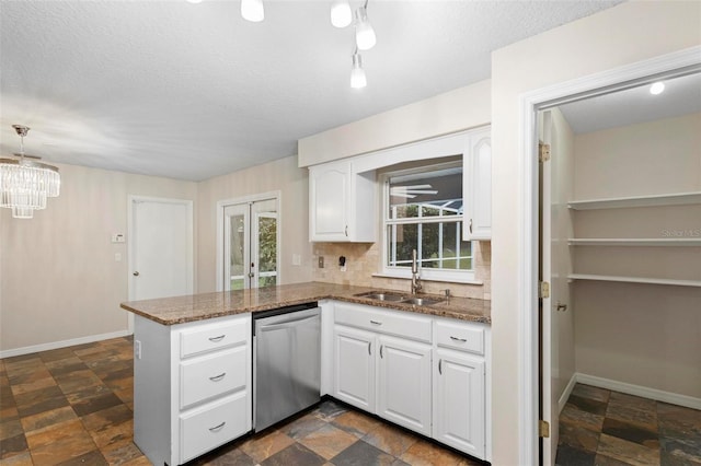 kitchen featuring sink, stainless steel dishwasher, kitchen peninsula, dark stone counters, and white cabinets