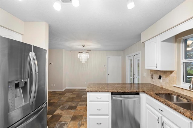 kitchen with kitchen peninsula, white cabinetry, decorative light fixtures, and appliances with stainless steel finishes