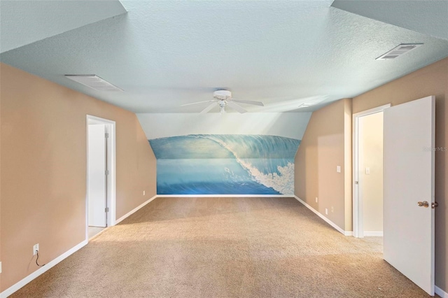 additional living space featuring a textured ceiling, light colored carpet, ceiling fan, and lofted ceiling