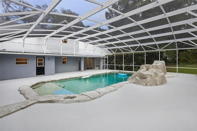 view of swimming pool featuring glass enclosure and a patio