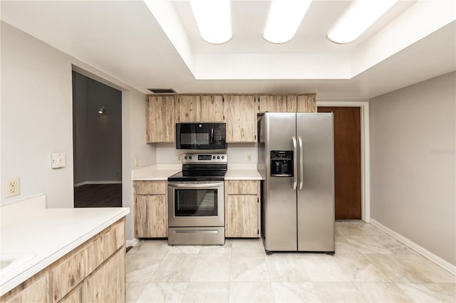 kitchen featuring stainless steel appliances, a raised ceiling, and light brown cabinets