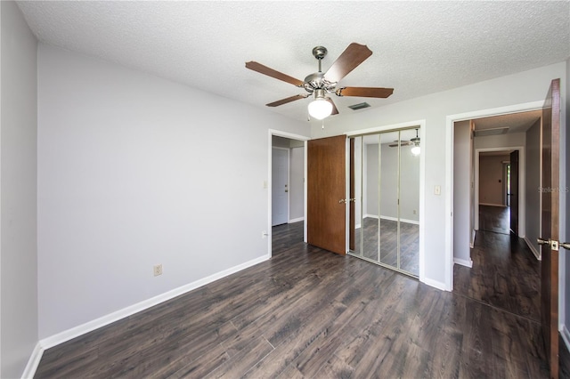 unfurnished bedroom with ceiling fan, dark hardwood / wood-style floors, a closet, and a textured ceiling