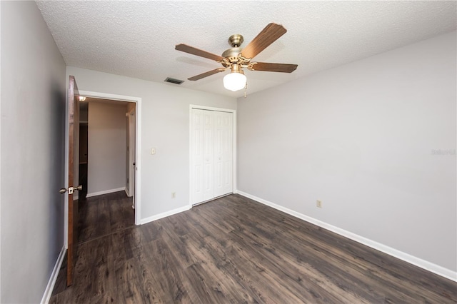 unfurnished bedroom featuring ceiling fan, dark wood-type flooring, a textured ceiling, and a closet