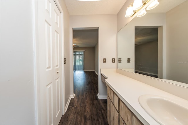 bathroom with vanity, a notable chandelier, wood-type flooring, and a textured ceiling