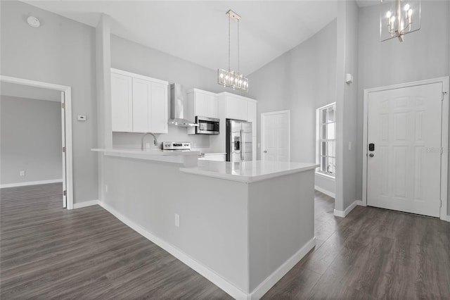 kitchen featuring wall chimney exhaust hood, appliances with stainless steel finishes, hanging light fixtures, and white cabinets