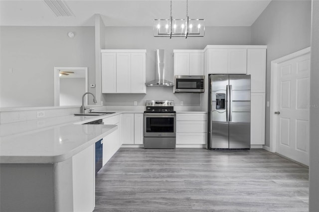 kitchen with appliances with stainless steel finishes, sink, wall chimney exhaust hood, and kitchen peninsula