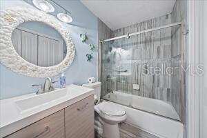 full bathroom with toilet, shower / bath combination with glass door, and vanity