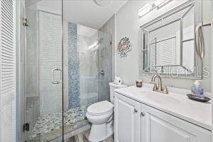 bathroom with a shower with door, toilet, and vanity