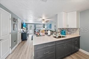 kitchen with light hardwood / wood-style flooring, gray cabinetry, kitchen peninsula, white cabinetry, and ceiling fan