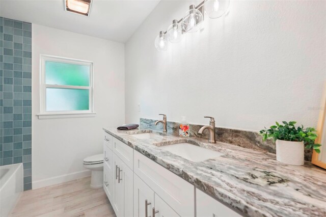 bathroom featuring toilet, hardwood / wood-style flooring, vanity, and a washtub