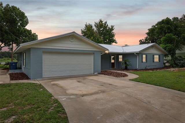 single story home featuring a garage and a lawn