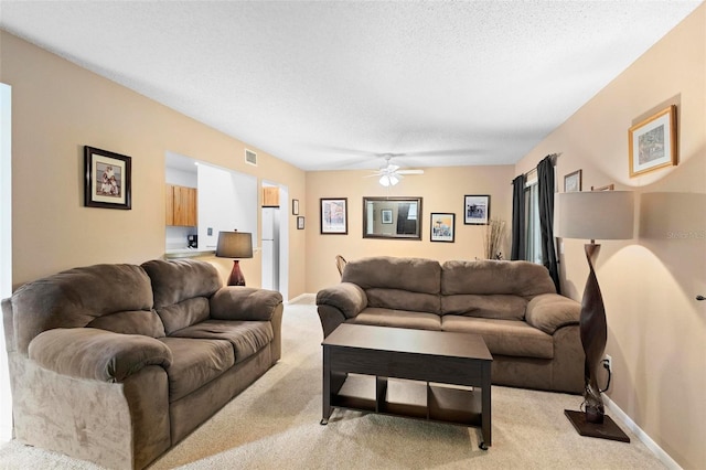 carpeted living room featuring a textured ceiling and ceiling fan