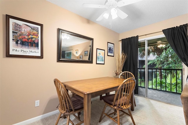 dining space featuring a textured ceiling, light colored carpet, and ceiling fan