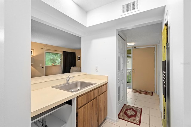 kitchen featuring sink, a textured ceiling, and light tile patterned floors