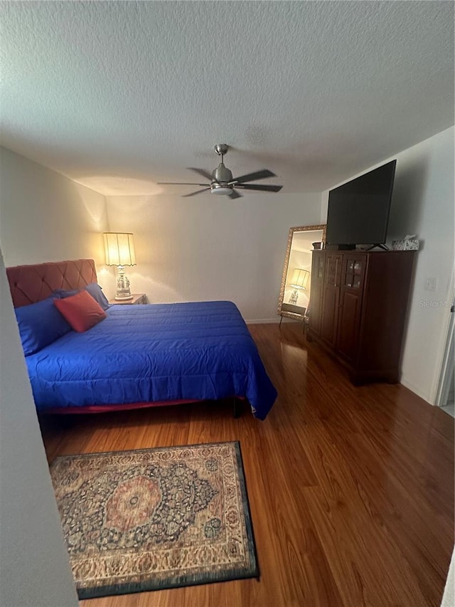 bedroom with a textured ceiling, hardwood / wood-style flooring, and ceiling fan