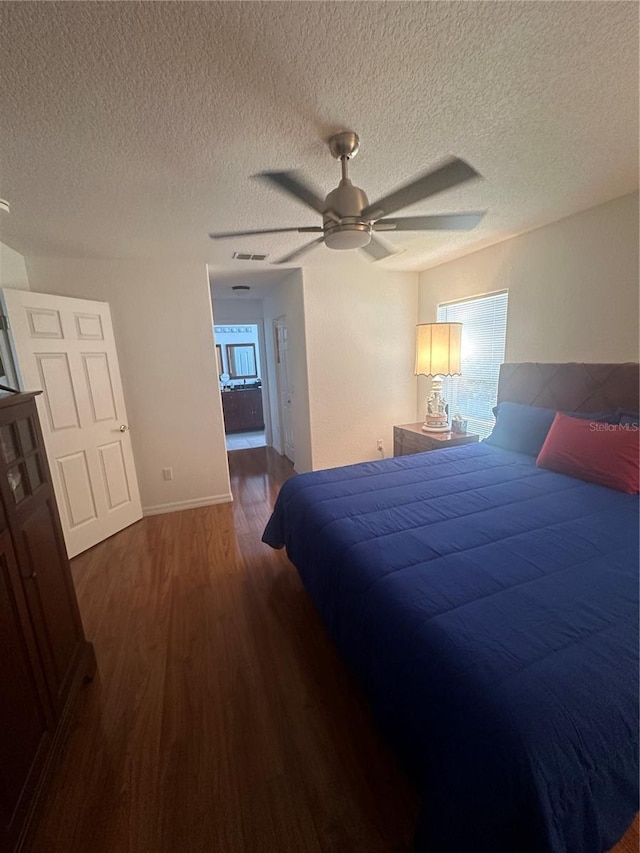 bedroom with ceiling fan, dark hardwood / wood-style floors, and a textured ceiling