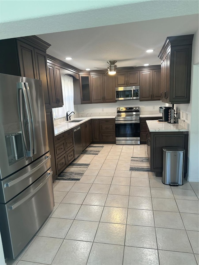 kitchen featuring dark brown cabinetry, sink, light tile patterned floors, and stainless steel appliances