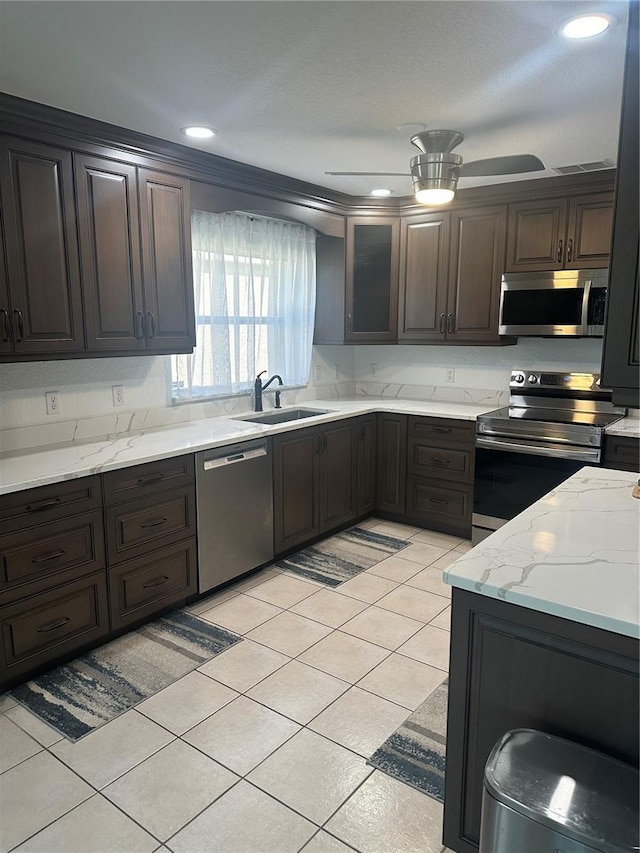 kitchen with dark brown cabinetry, ceiling fan, sink, light tile patterned floors, and appliances with stainless steel finishes