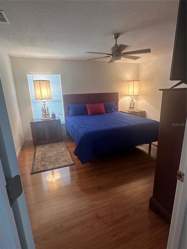 bedroom with wood-type flooring, a textured ceiling, and ceiling fan