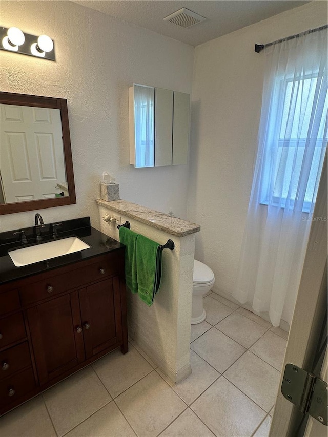 bathroom with tile patterned flooring, vanity, and toilet