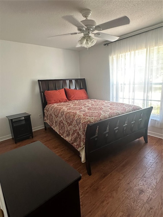 bedroom with a textured ceiling, ceiling fan, and dark hardwood / wood-style floors