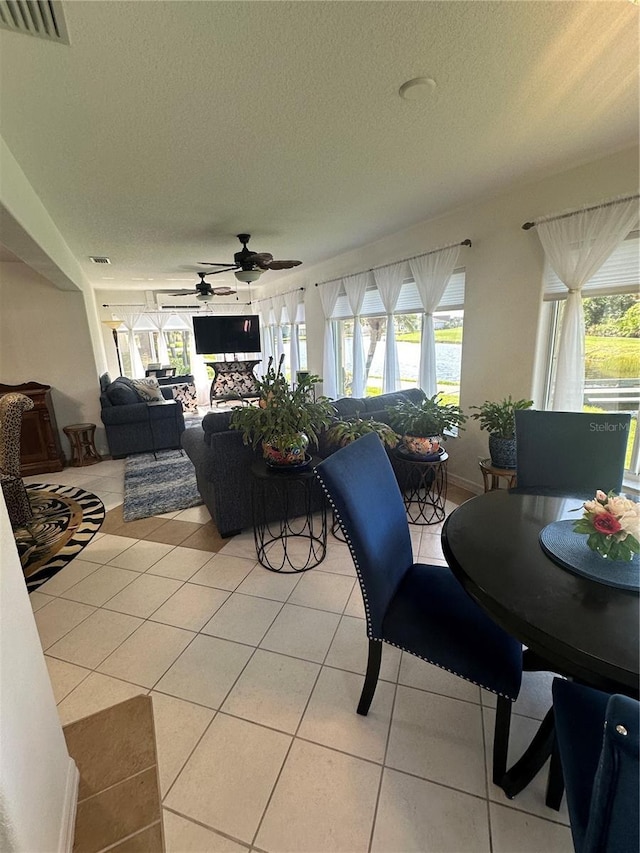 dining space featuring ceiling fan, light tile patterned floors, and a textured ceiling