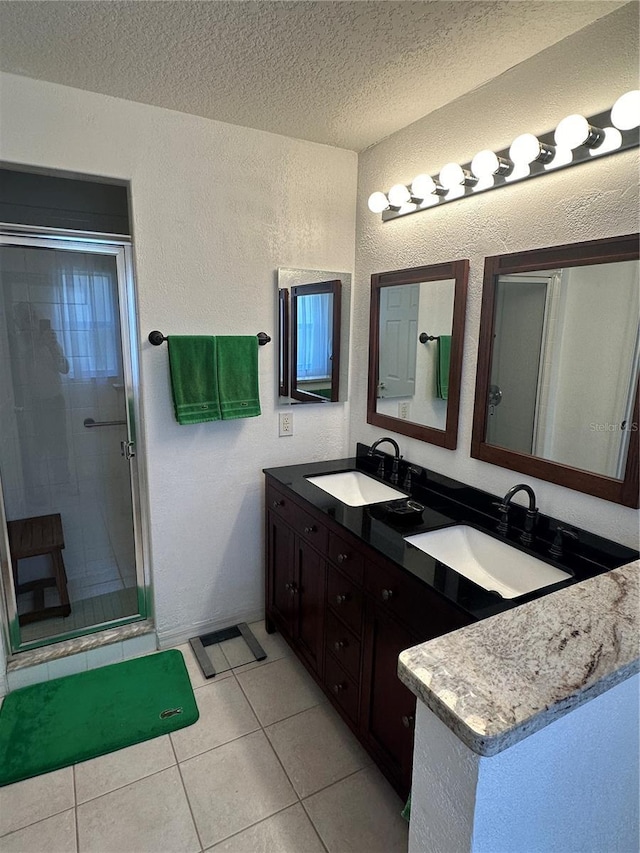 bathroom featuring tile patterned flooring, vanity, a textured ceiling, and walk in shower