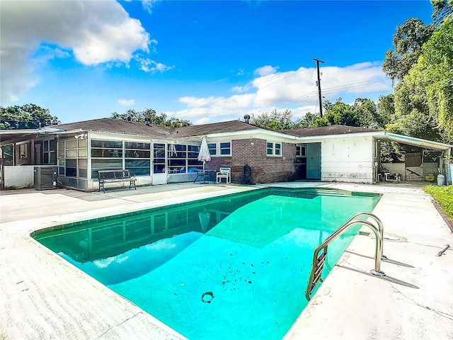 view of swimming pool with central AC unit, a sunroom, and a patio