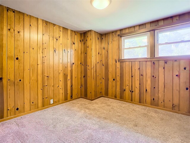 carpeted spare room featuring wood walls