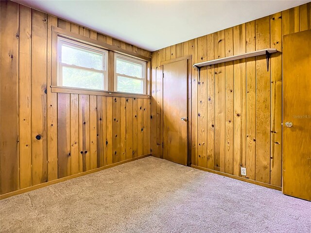 carpeted empty room with wood walls