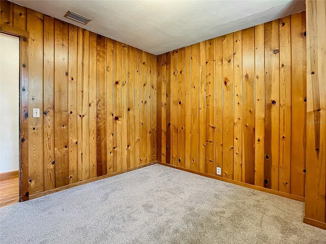 empty room with carpet floors and wood walls