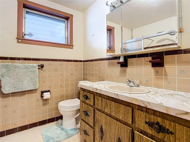 bathroom featuring vanity, toilet, tile patterned flooring, and tile walls