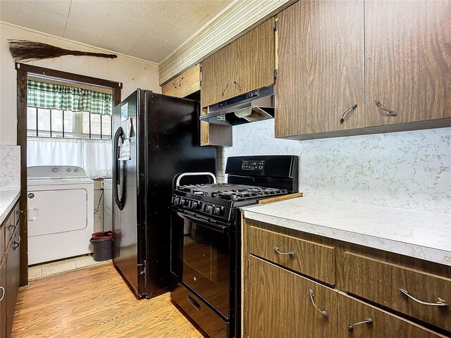 kitchen featuring washer and clothes dryer, decorative backsplash, light wood-type flooring, and black appliances