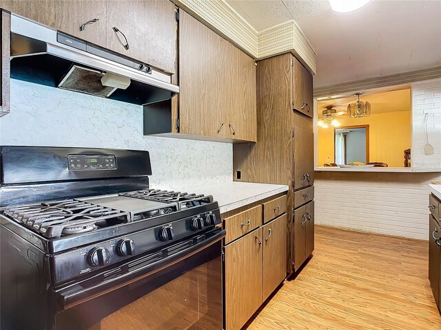 kitchen with backsplash, light hardwood / wood-style flooring, hanging light fixtures, and black gas stove