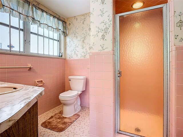 bathroom featuring tile walls, tile patterned flooring, vanity, toilet, and a shower with door